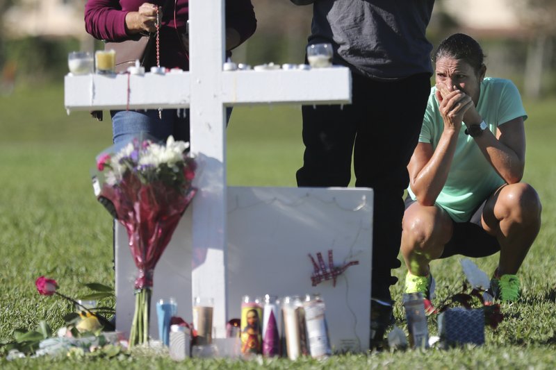 Maria Creed is overwhelmed with emotion as she crouches in front of one of the memorial crosses at Pine Trails Park in Parkland, Fla., Friday, Feb. 16, 2018, that were placed for the victims of the Wednesday shooting at Marjory Stoneman Douglas High School. Creed’s son, Michael Creed, is a sophomore at the school. (Amy Beth Bennett/South Florida Sun-Sentinel via AP)