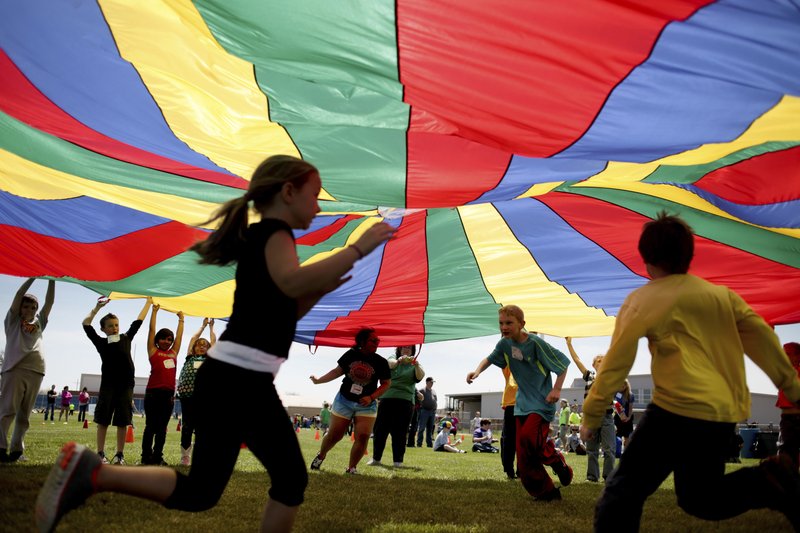 Elementary school third graders run under a rainbow colored tarp during Fitness Day. Photo via AP.