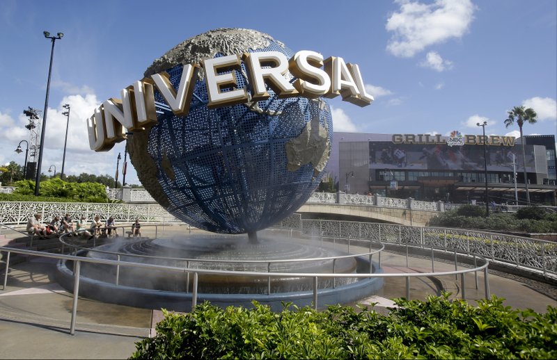 In this Oct. 22, 2015 file photo, park guests relax and cool off with a water mist under the globe at Universal Studios City Walk in Orlando, Fla. A lawsuit brought by a Guatemalan family whose father died after going on a ride says Universal Orlando Resort should have put warning signs in Spanish. Photo via AP/John Raoux.