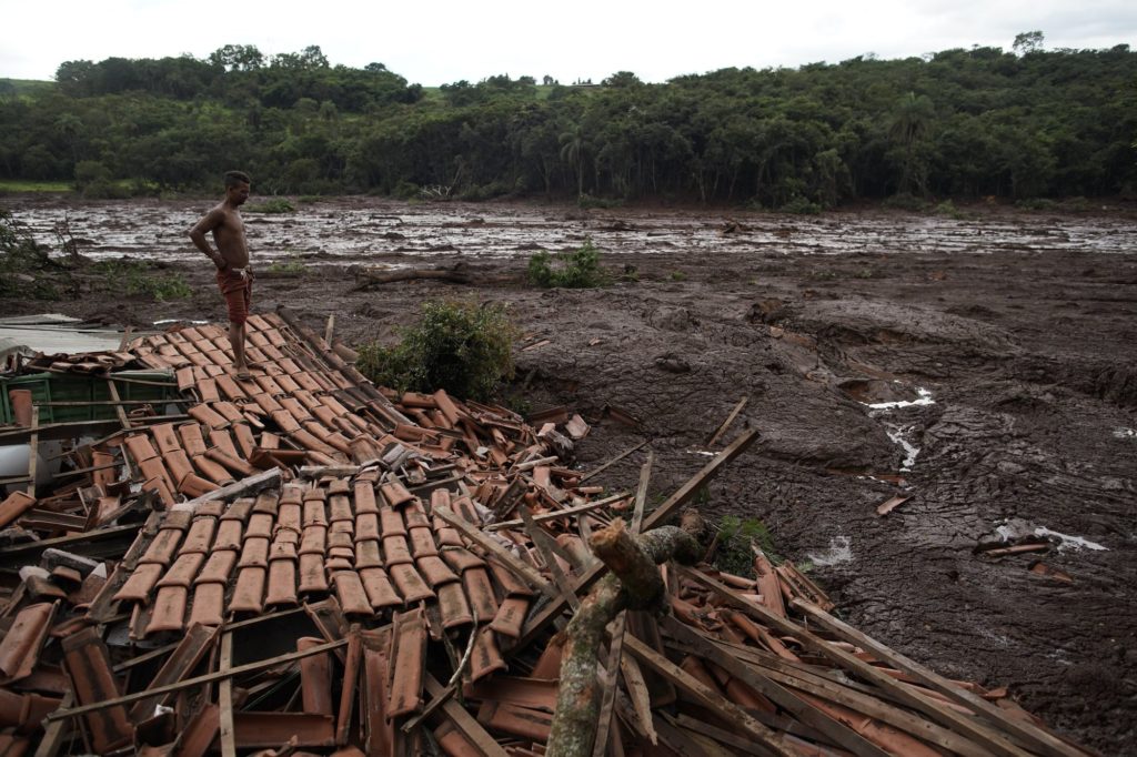 Emerson dos Santos stands on the debris of her mother's house in Brumadinho, Brazil, Saturday, Jan. 26, 2019. Rescuers in helicopters on Saturday searched for survivors while firefighters dug through mud in a huge area in southeastern Brazil buried by the collapse of a dam holding back mine waste, with at least nine people dead and up to 300 missing. Dos Santos' mother was not in the house and survived the tragedy. (AP Photo/Leo Correa)