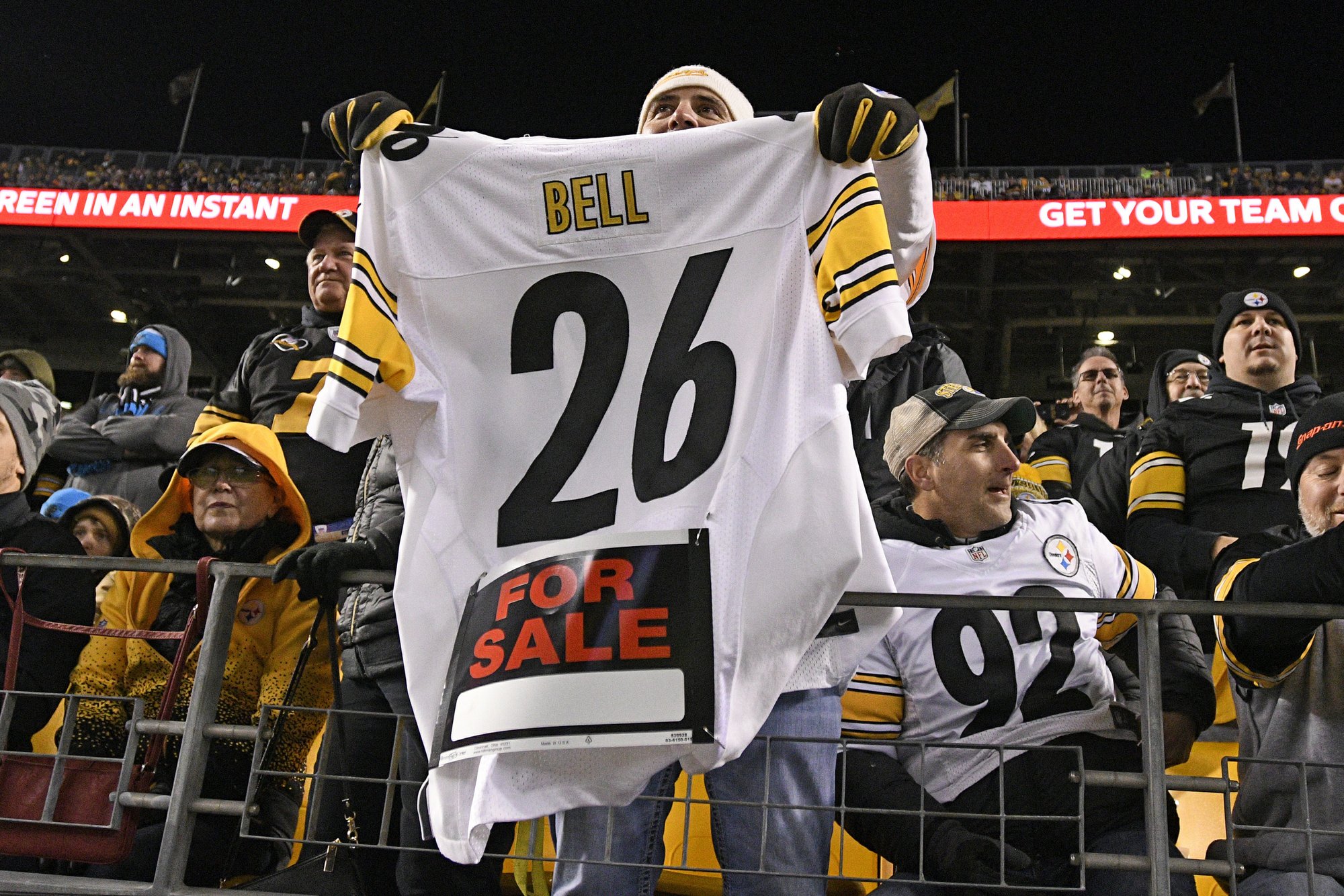 FILE - In this Nov. 8, 2018, file photo, a Pittsburgh Steelers fan holds a Le'Veon Bell jersey during the second half of an NFL football game between the Steelers and the Carolina Panthers in Pittsburgh. The steady exodus of mid-level veterans from the NFL is one element of a long-standing tension between players and the league over the structuring of contracts. The contract holdouts by Bell and Earl Thomas this season put the issue into vivid focus. (AP Photo/Don Wright, File)