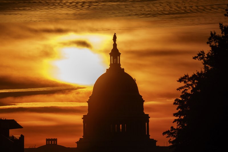 FILE- In this Oct. 26, 2018, file photo the rising sun silhouettes the U.S. Capitol dome at daybreak in Washington. A new government report says that the U.S. budget deficit is set to hit $897 billion this year and predicts that economic growth will slow as the effects of President Donald Trump’s tax cut on business investment begin to drop off. (AP Photo/Alex Brandon, File)