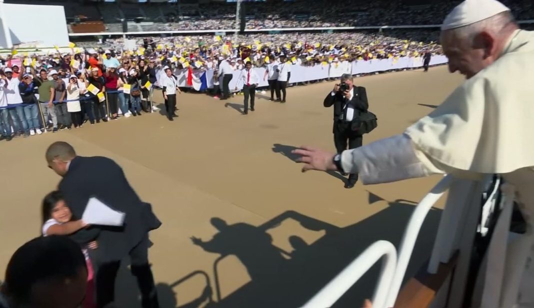 In this image made from video provided by Vatican Media, Pope Francis reaches for a letter from a young girl who broke through police barriers, in Abu Dhabi, United Arab Emirates, Tuesday, Feb. 5, 2019. Pope Francis has praised the courage of the young girl who dashed out of the crowd so quickly that police couldn't catch her. 