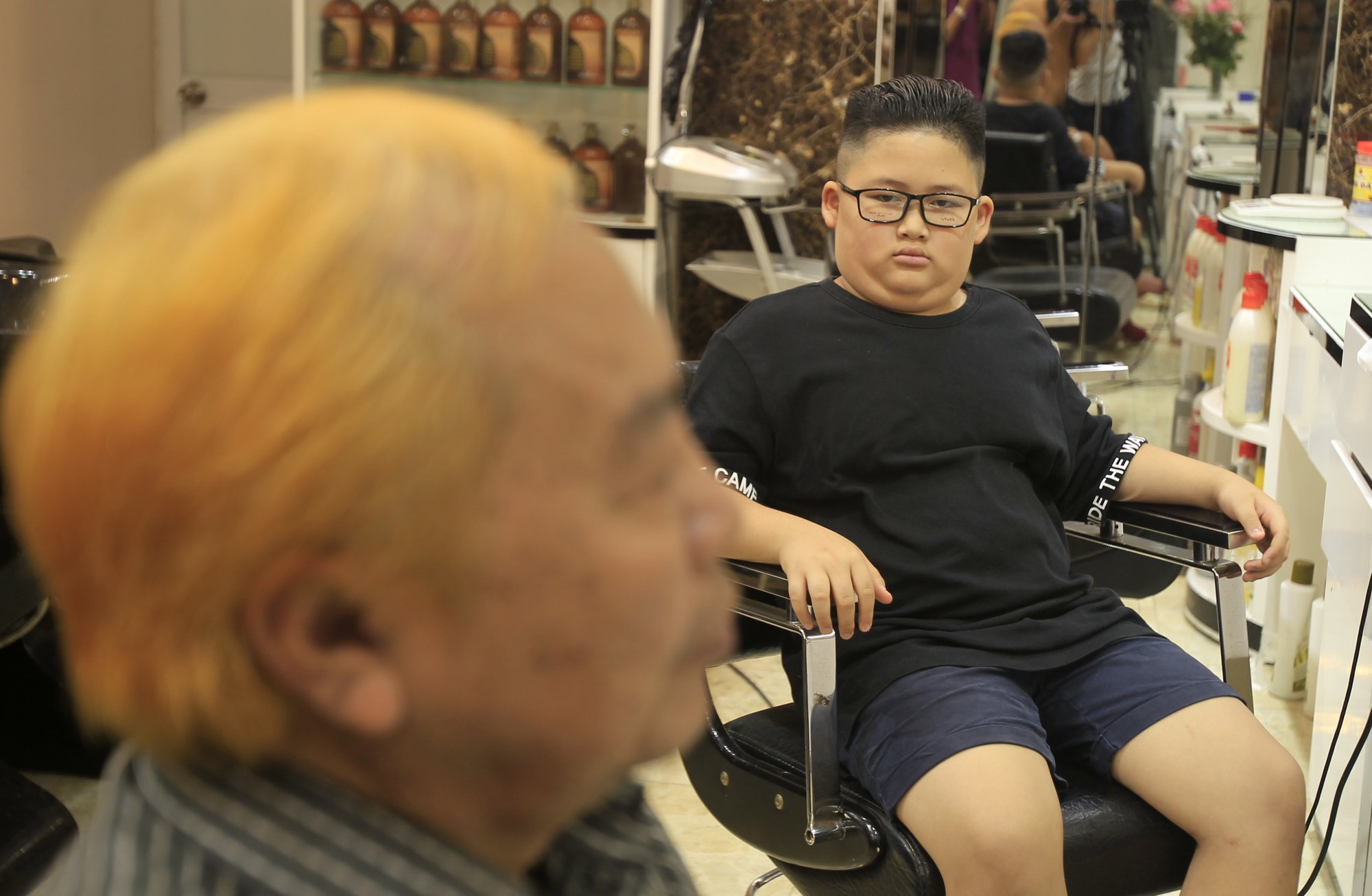 Le Phuc Hai, 66, left, and To Gia Huy, 9, sit after having Trump and Kim haircuts in Hanoi, Vietnam, on Tuesday, Feb.19, 2019. U.S. President Donald Trump and North Korean leader Kim Jong Un have become the latest style icons in Hanoi, a week before their second summit is to be held in the capital city of Vietnam.(AP Photo/Hau Dinh)