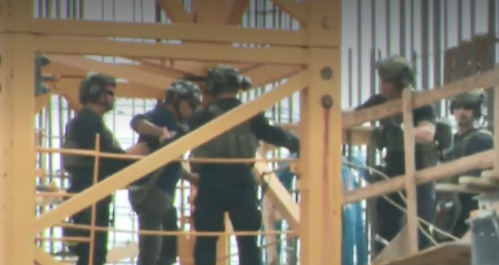 Man being apprehended on the crane. (CBS News photo)