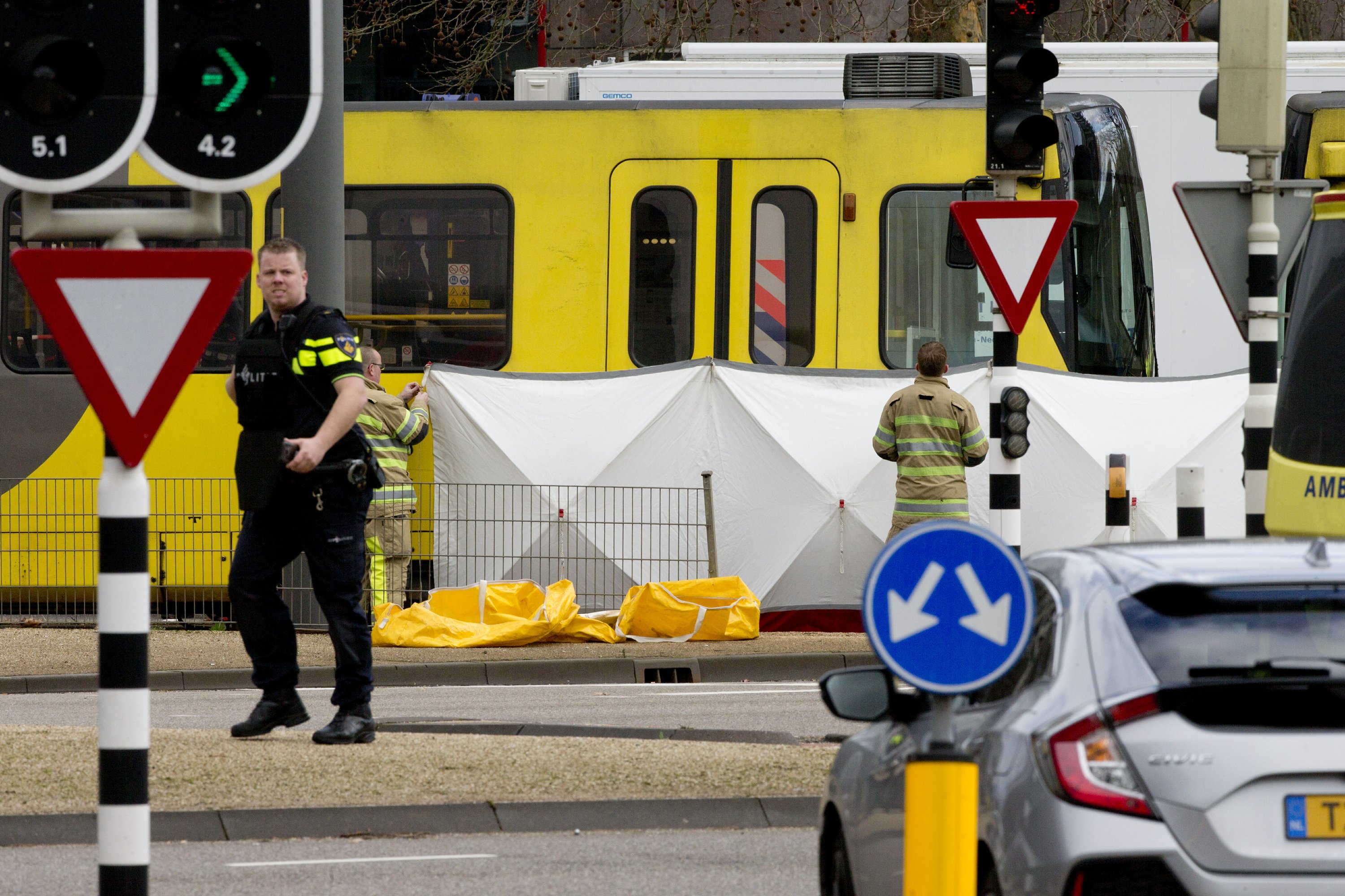 Rescue workers install a screen on the spot where a body was covered with a white blanket following a shooting in Utrecht, Netherlands, Monday, March 18, 2019. Police in the central Dutch city of Utrecht say on Twitter that "multiple" people have been injured as a result of a shooting in a tram in a residential neighborhood. (AP Photo/Peter Dejong)