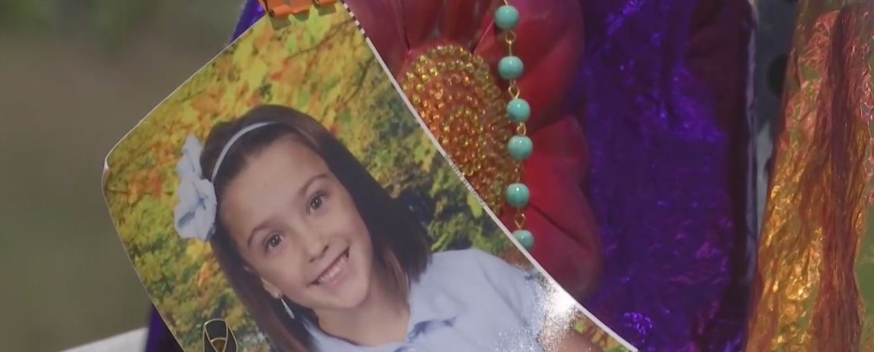 Attendee holds a photo of the 8-year-old girl who died in a hit-and-run crash on March 25. (Credit: WINK News)