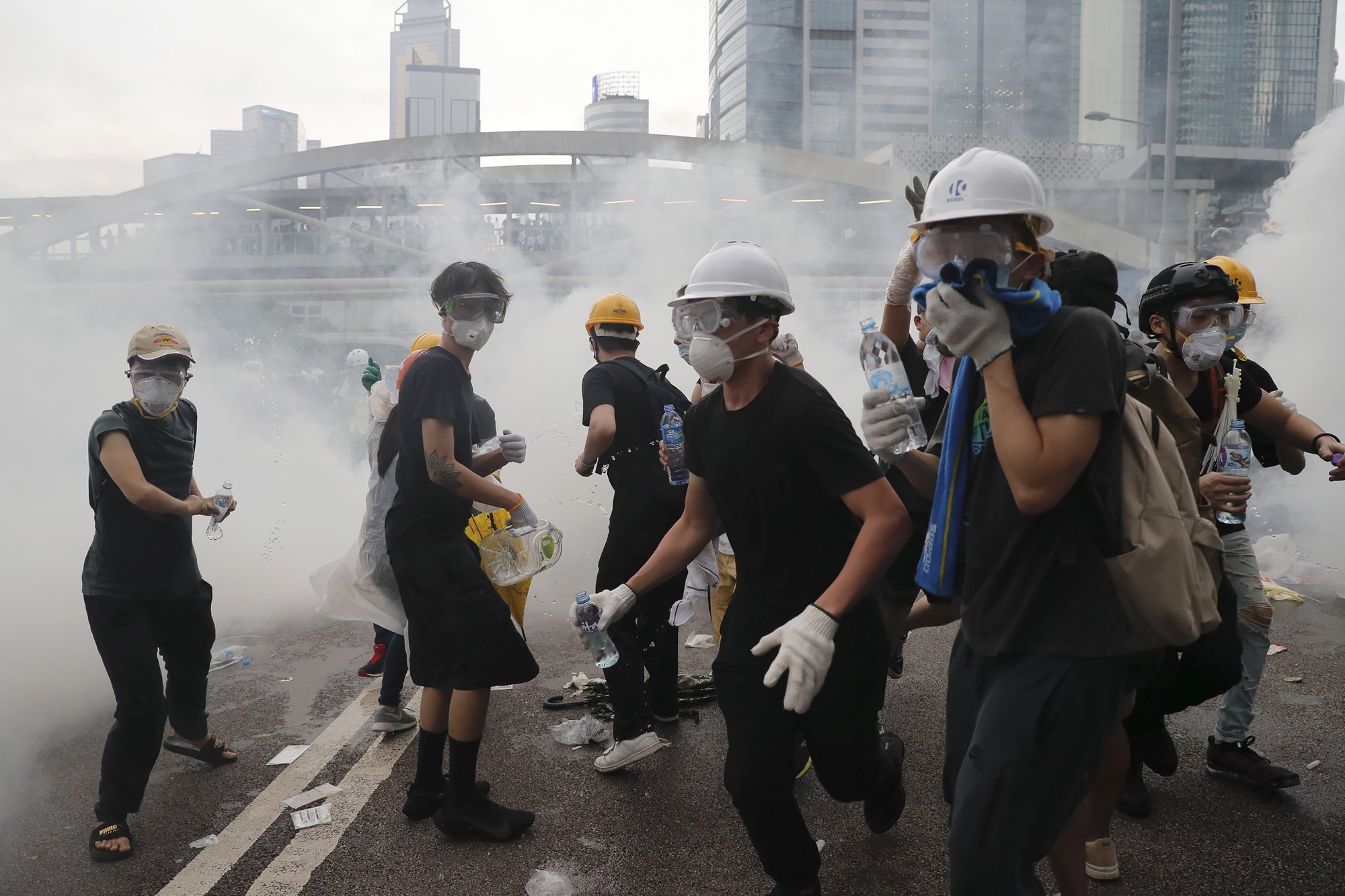 Demonstrators react to a cloud of tear gas near the Legislative Council in Hong Kong, Wednesday, June 12, 2019. Hong Kong police fired tear gas and high-pressure water hoses against protesters who had massed outside government headquarters Wednesday in opposition to a proposed extradition bill that has become a lightning rod for concerns over greater Chinese control and erosion of civil liberties in the semiautonomous territory. (AP Photo/Kin Cheung)