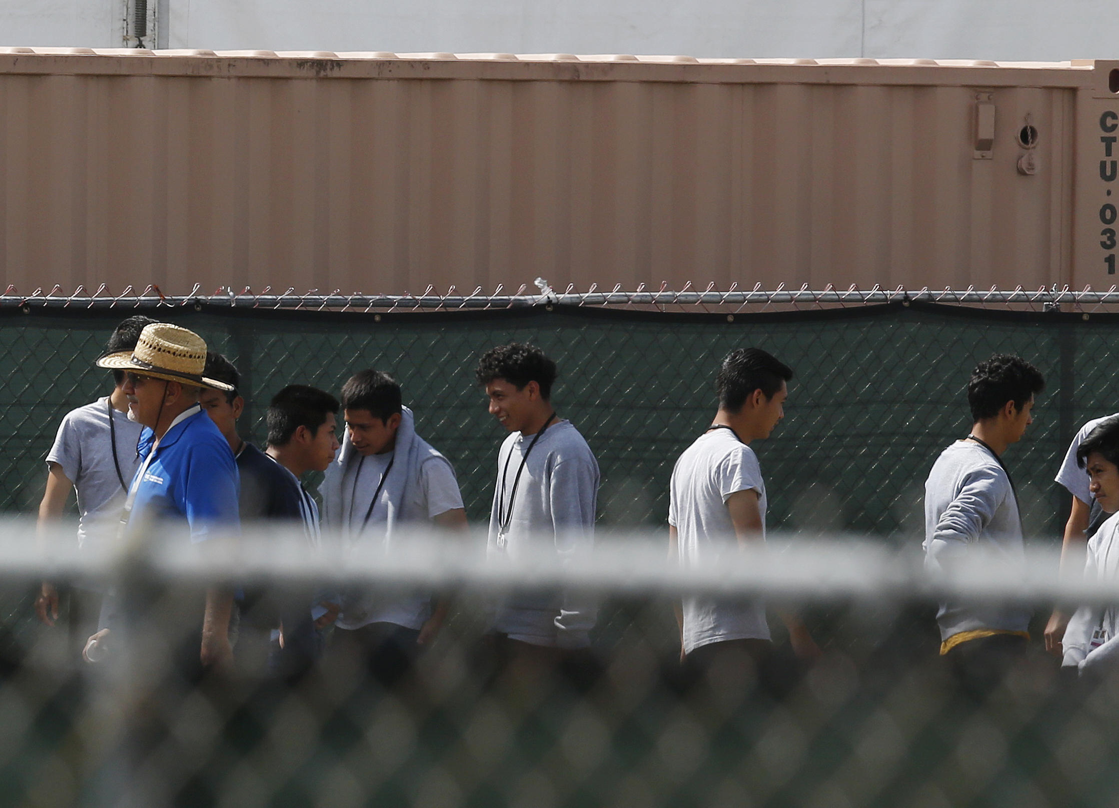 Migrant children walk outside at the Homestead Temporary Shelter for Unaccompanied Children a former Job Corps site that now houses them, on Friday, June 22, 2018, in Homestead, Fla. U.S. officials provided a glimpse into the South Florida facility housing more than 1,000 teen-age migrants, seeking to dispel any suggestions that children are being mistreated. The tour included dorm-style buildings where children sleep up to 12 per room in steel-framed bunk beds, and warehouse-sized, air-conditioned white tents where minors attend classes and watch movies. (AP Photo/Brynn Anderson)