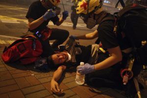Medical workers help a protester in pain from tear gas fired by policemen on a street in Hong Kong, Sunday, July 21, 2019. (AP Photo/Bobby Yip)