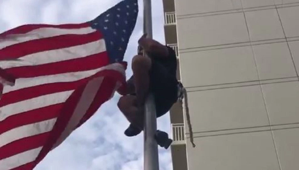 Navy SEAL climbs flag poll to fix American flag at Virginia Beach Navy SEAL Oceanfront monument. (Credit: CBS via Dan Raso)