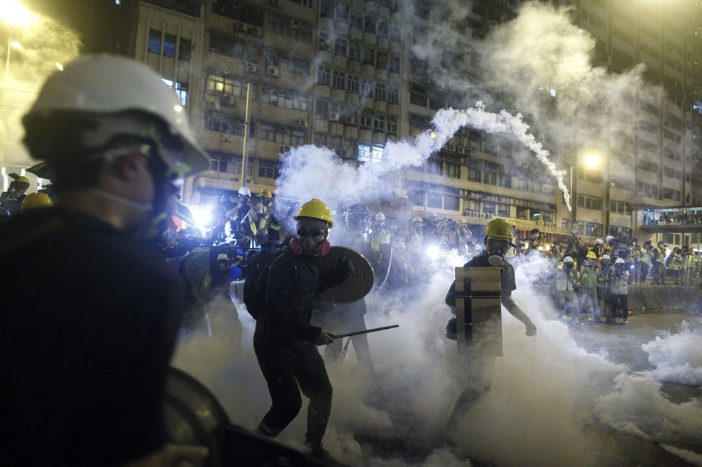 Protesters react to tear gas during a confrontation with riot police in Hong Kong Sunday, July 21, 2019. Hong Kong police launched tear gas at protesters Sunday after a massive pro-democracy march continued late into the evening. The action was the latest confrontation between police and demonstrators who have taken to the streets to protest an extradition bill and call for electoral reforms in the Chinese territory. (Eric Tsang/HK01 via AP)