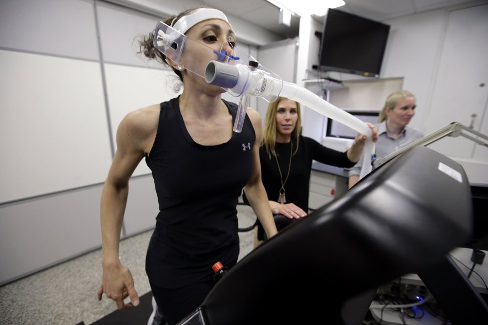 In this April 23, 2019 photo, research scientist Leila Walker, left, is assisted by nutritional physiologist Holly McClung, center, as they demonstrate equipment designed to evaluate fitness levels in female soldiers, not shown, who have joined elite fighting units such the Navy Seals, at the U.S. Army Research Institute of Environmental Medicine, at the U.S. Army Combat Capabilities Development Command Soldier Center, in Natick, Mass. (AP Photo/Steven Senne)