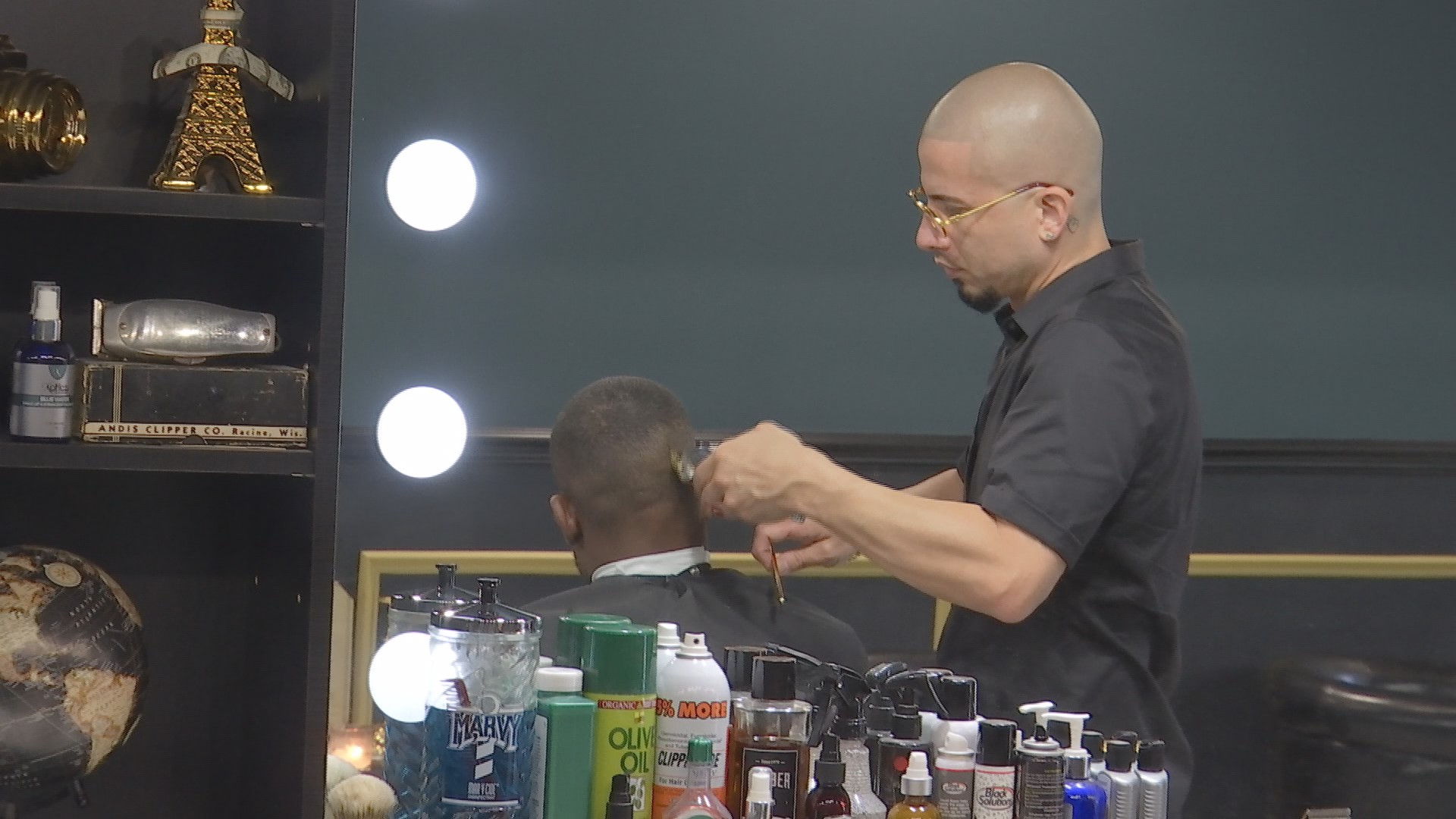 Ivan Suarez as he cuts the hair of a patron at his barber shop. (Credit: WINK News)
