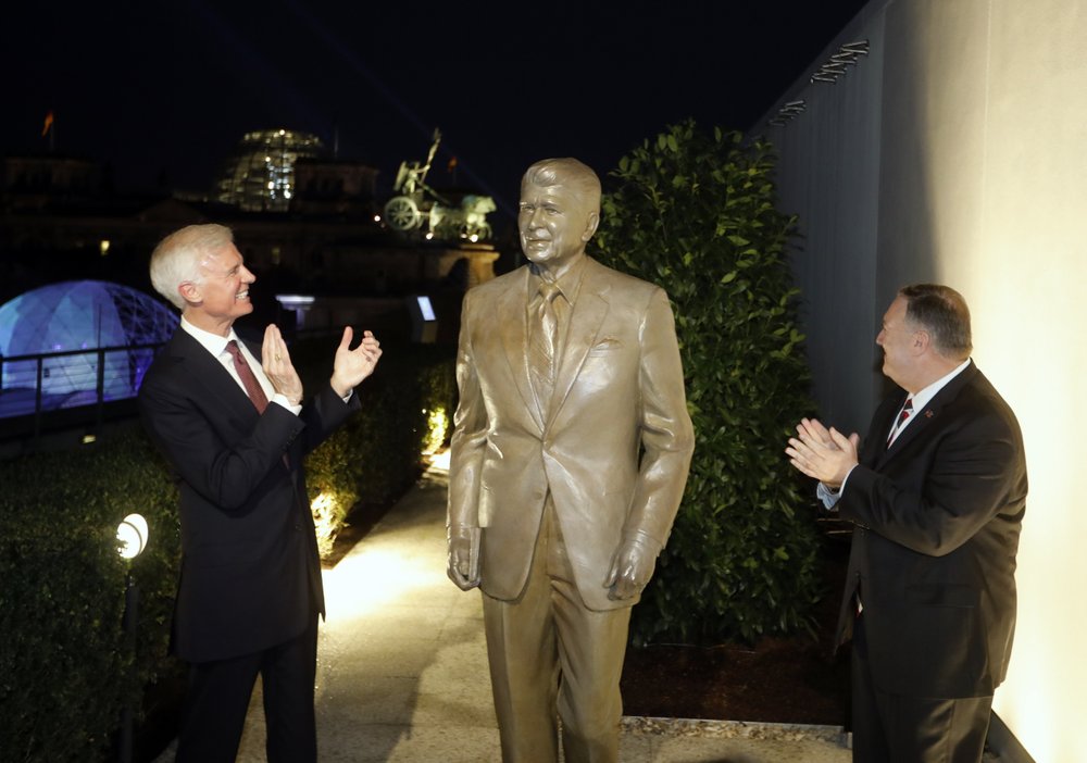 Together with United States Ambassador in Germany Richard Grenell, right, and Fred Ryan Board Chairman of the Reagan Foundation, left, Secretary of State Mike Pompeo unveils a statue of former President Ronald Reagan on the top of United States embassy in Berlin, Germany, Friday, Nov. 7, 2019. (AP Photo/Markus Schreiber)
