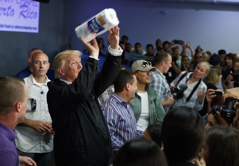 FILE - In this Oct. 3, 2017, file photo, President Donald Trump tosses paper towels into a crowd at Calvary Chapel in Guaynabo, Puerto Rico, after Hurricane Maria devastated the region. Ahead of Vice President Mike Pence's Latinos for Trump rally in central Florida, state Democrats have paid for a billboard showing an image of the president tossing paper towels, seen like this photo, at a Puerto Rican church after the island was devastated by Hurricane Maria. (AP Photo/Evan Vucci, File)