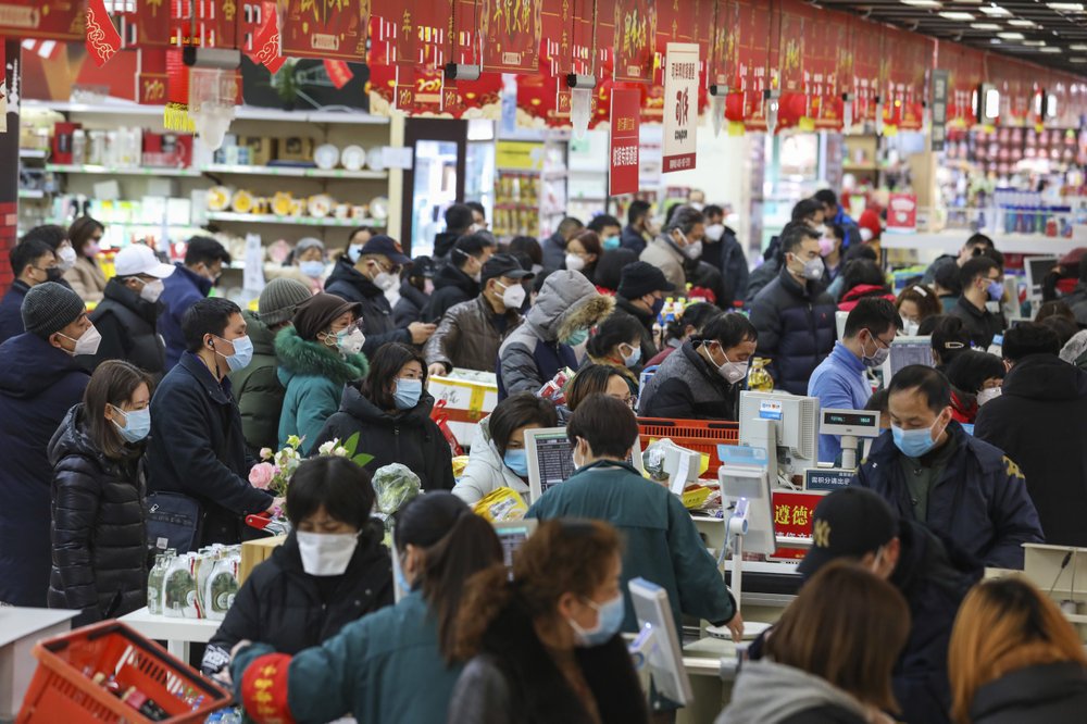 Shoppers wearing face masks pay for their groceries at a supermarket in Wuhan in central China's Hubei province, Saturday, Jan. 25, 2020. The virus-hit Chinese city of Wuhan, already on lockdown, banned most vehicle use downtown and Hong Kong said it would close schools for two weeks as authorities scrambled Saturday to stop the spread of an illness that is known to have infected more than 1,200 people and killed 41, according to officials. (Chinatopix via AP)